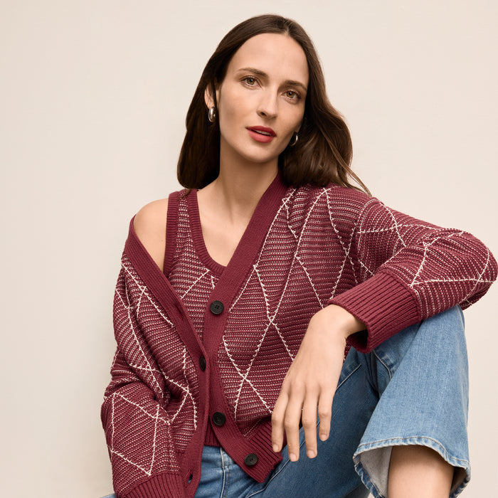Woman wearing a patterned maroon cardigan against a beige background