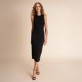 Woman wearing a black sleeveless dress against a beige background | Lead