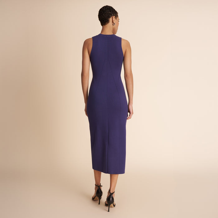 Woman wearing a sleeveless purple dress against a beige background