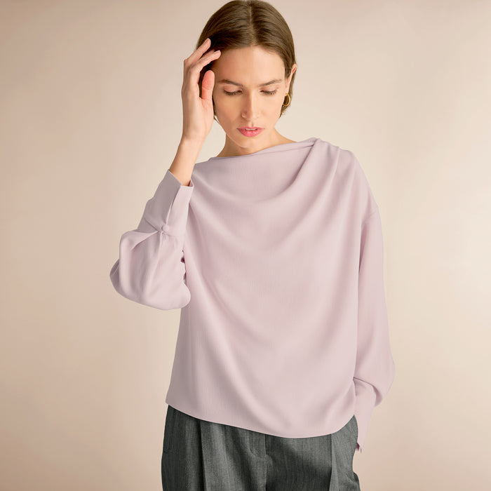 Woman wearing a light purple blouse against a beige background | Lead