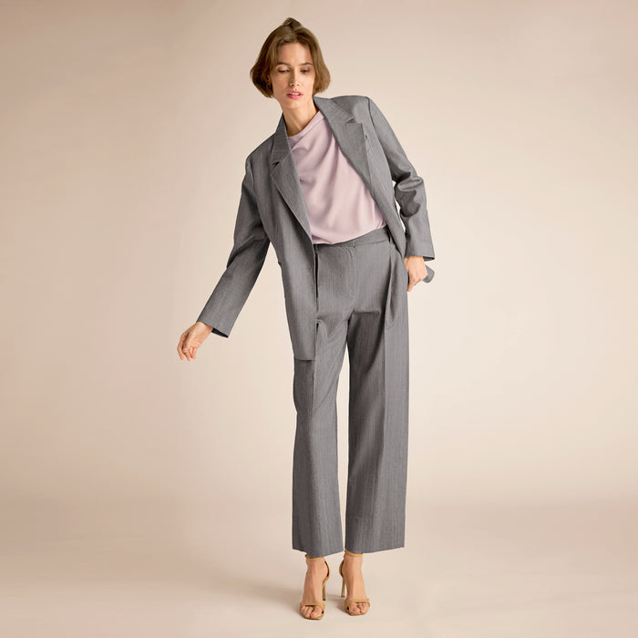 Woman wearing a gray suit with a light pink top on a beige background