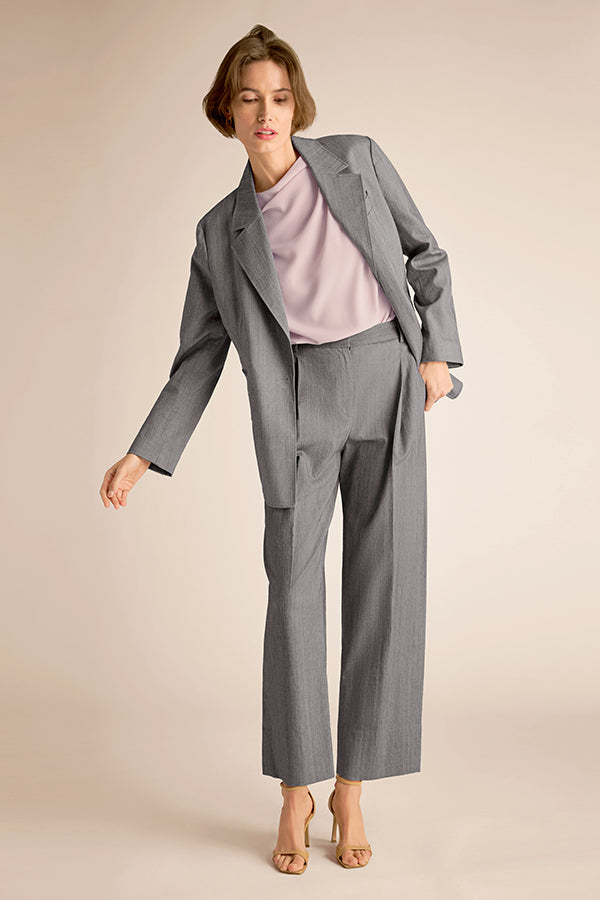 Woman wearing a gray suit with a light pink top on a beige background | Exclude