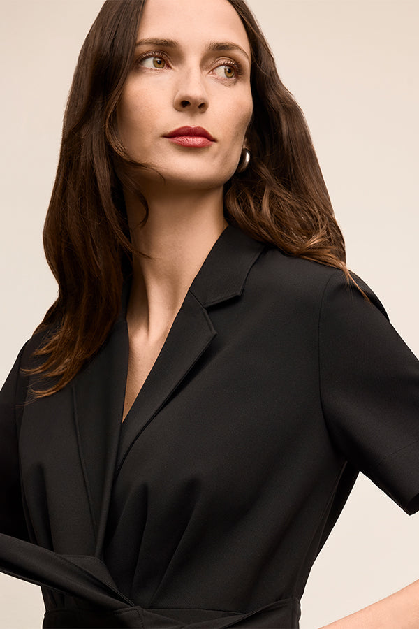 Woman wearing a black outfit against a beige background | Exclude