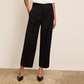 Person wearing black wide-leg pants against a beige background | Lead