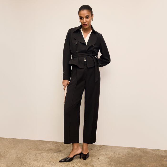 Woman wearing a black suit with a white shirt against a beige background