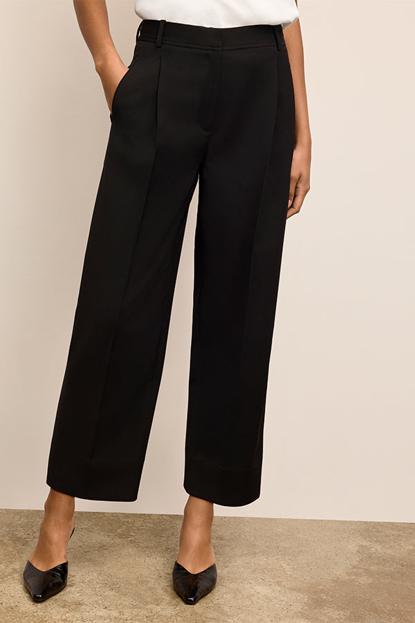 Person wearing black wide-leg pants against a beige background | Exclude | Grid
