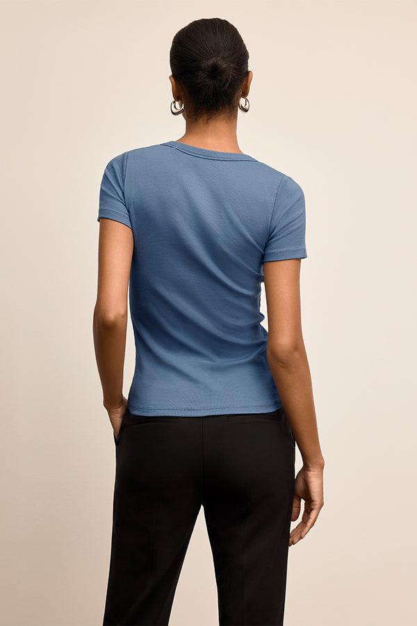 Person wearing a blue t-shirt and black pants on a beige background | Exclude | Grid Hover