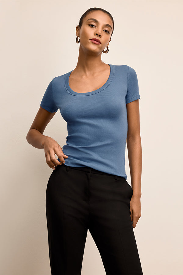Woman wearing a blue top and black pants against a beige background | Exclude | Grid