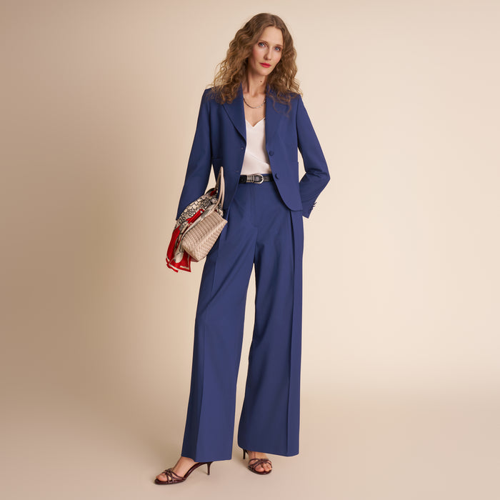 Woman wearing a blue suit with a beige background | Lead