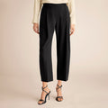 Black pants worn by a person on a beige background | Lead