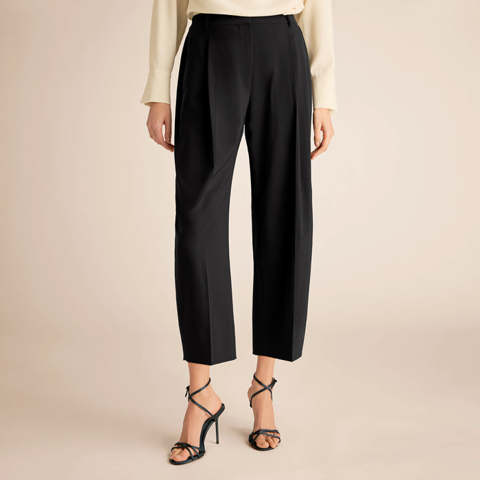 Black pants worn by a person on a beige background | Lead