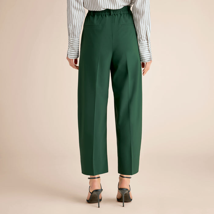 Green pants worn by a person on a beige background