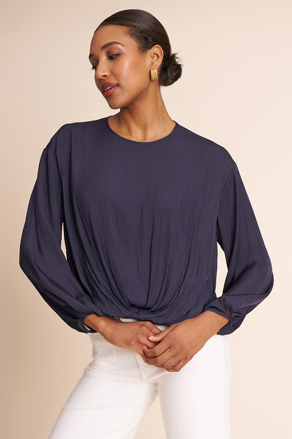 Woman wearing a navy blue long-sleeve top against a beige background | Exclude | Grid