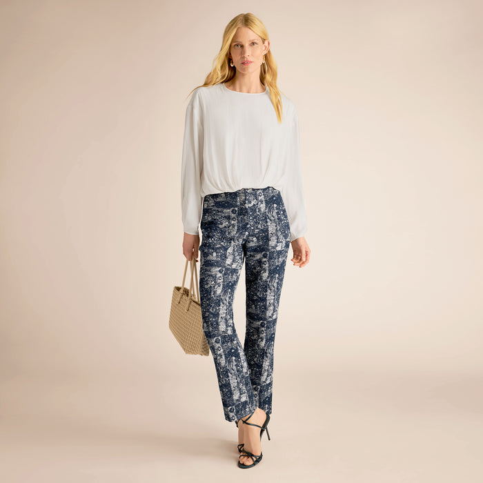 Woman wearing a white top and blue floral pants on a beige background