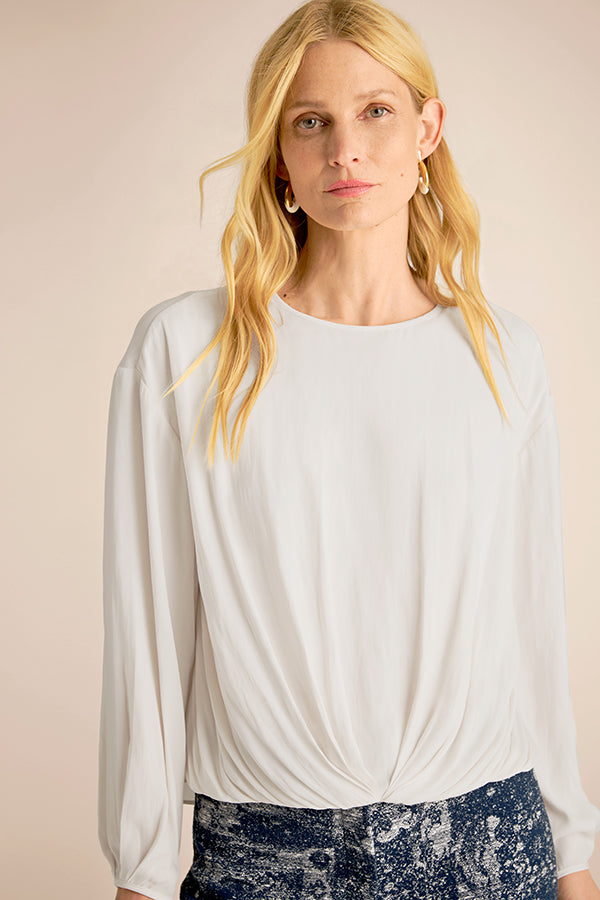 Woman wearing a light gray long-sleeve top against a beige background | Exclude | Grid