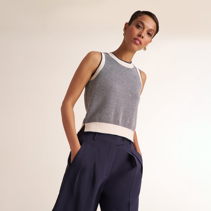 Woman wearing a navy and white knit tank top with navy pleated trouser pants