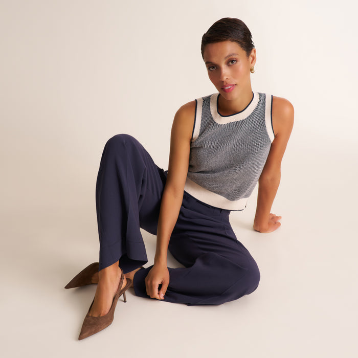 Woman wearing a navy and white knit tank top with navy pleated trouser pants | Exclude
