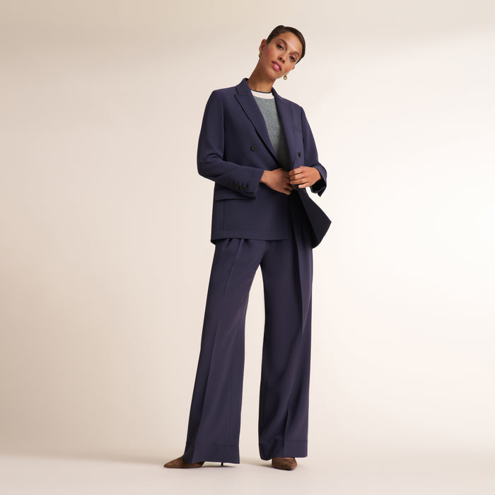Woman wearing a navy and white knit tank top with navy pleated trouser pants