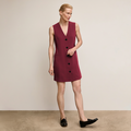 Woman wearing a burgundy dress with black buttons against a beige background  | Lead