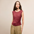 Woman wearing a maroon sleeveless top and beige pants against a beige background | Lead