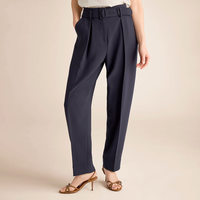 Navy blue pants worn by a person on a beige background | Lead