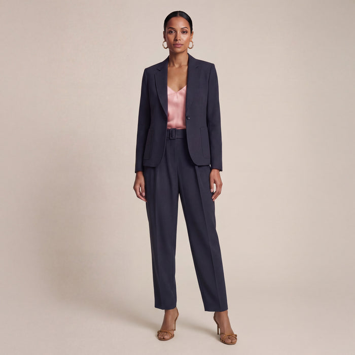 Woman wearing a navy suit on a beige background | Exclude