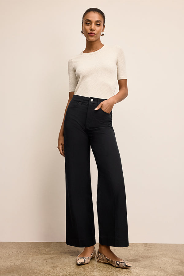 Woman wearing a white top and black pants against a beige background | Exclude | Grid
