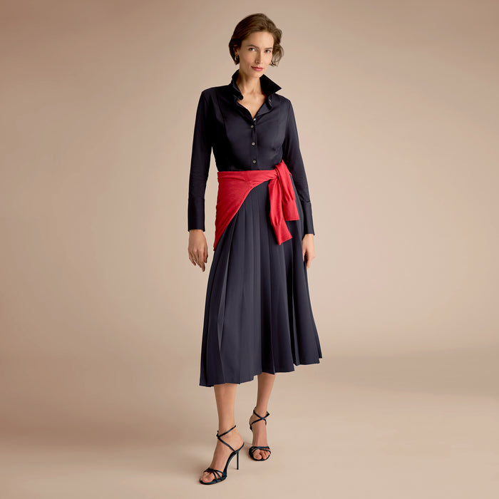 Woman wearing a black dress with a red sash on a beige background | Lead