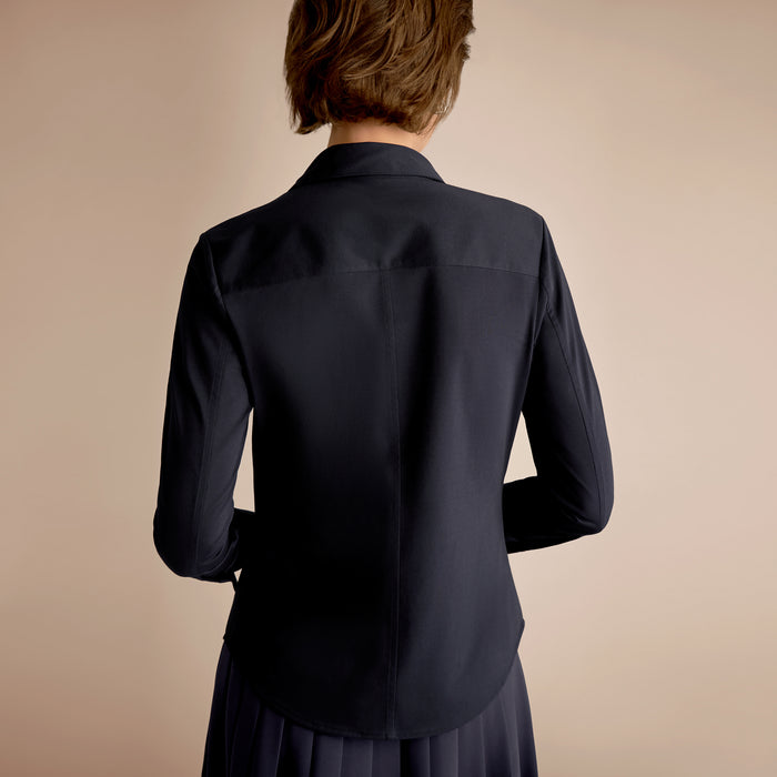 Person wearing a dark blue shirt against a beige background