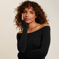 Woman wearing a black off-shoulder top against a beige background | Lead