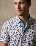 Man wearing a short-sleeve shirt with butterfly pattern against a neutral background