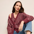 Woman wearing a patterned maroon cardigan against a beige background | Lead