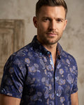 Man wearing a blue patterned shirt against a neutral background