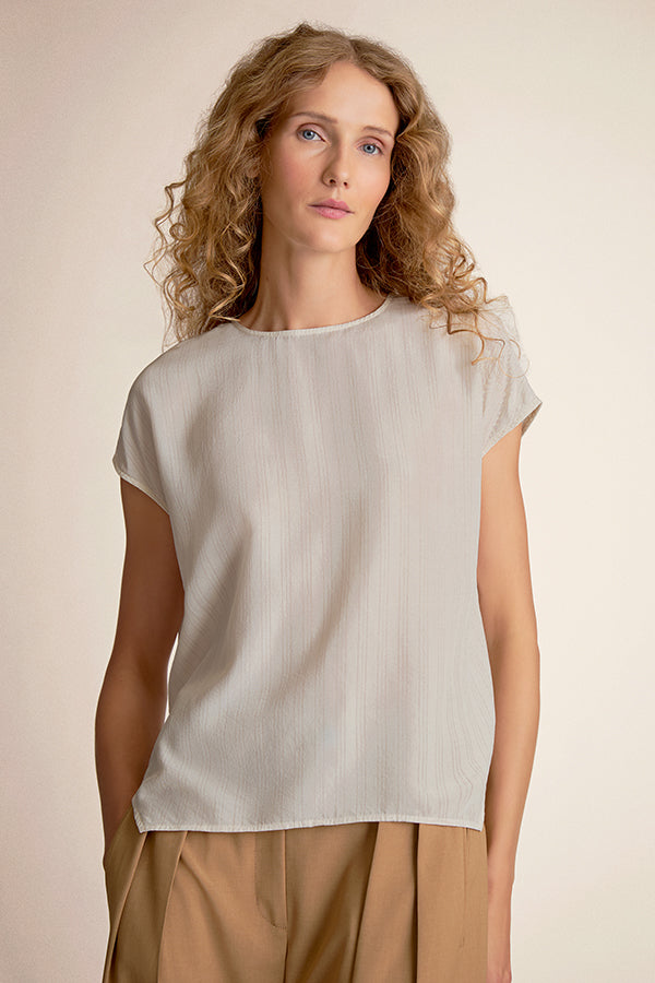 Woman wearing a light-colored top and beige pants against a neutral background | Grid | Exclude