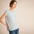 Woman wearing a striped shirt and jeans against a beige background | Lead