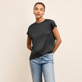 Woman wearing a black top and blue jeans on a beige background | Lead