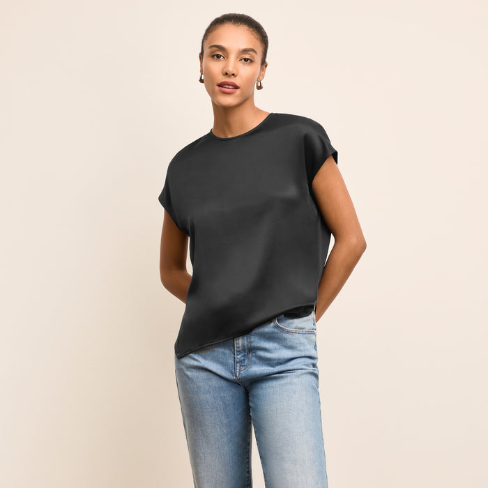Woman wearing a black top and blue jeans on a beige background | Lead