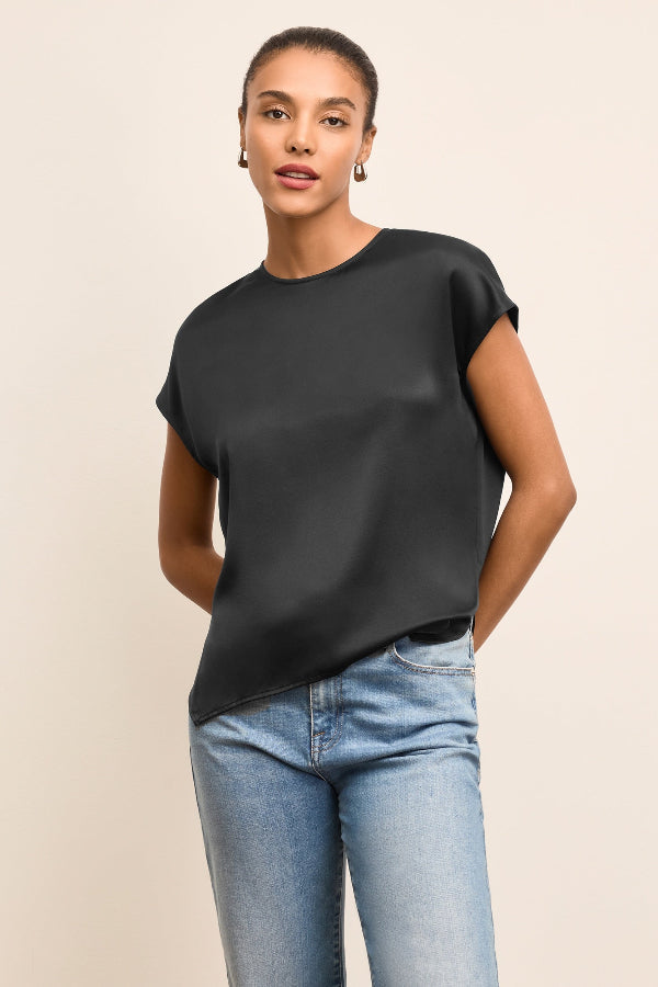 Woman wearing a black top and blue jeans on a beige background | Exclude | Grid