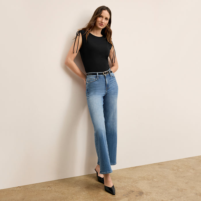 Front image of a woman wearing the Dotty Top in Black with denim jeans