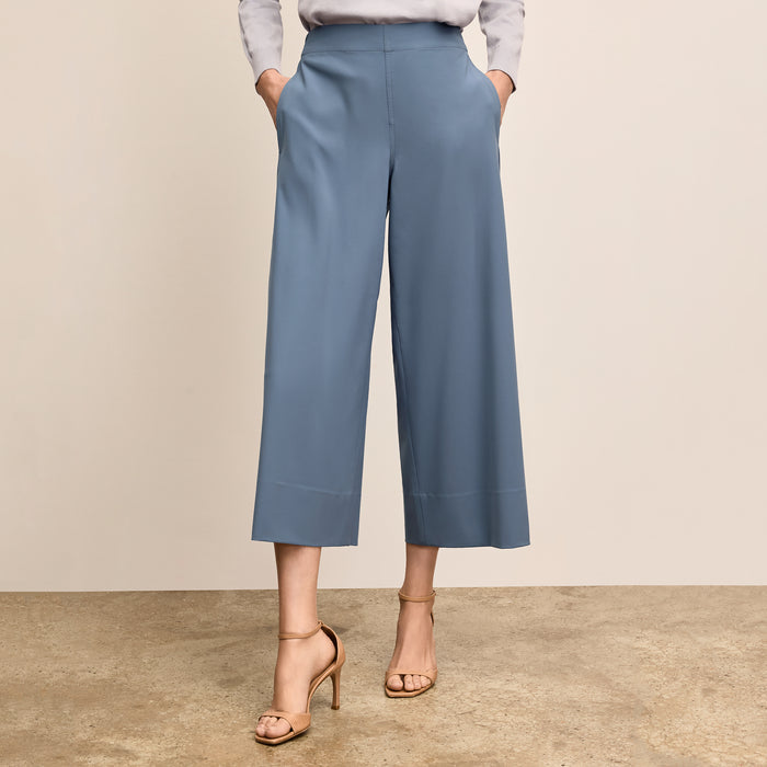 Person wearing light blue wide-leg pants and a gray top on a beige background | Lead