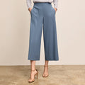 Person wearing light blue wide-leg pants and a gray top on a beige background | Lead