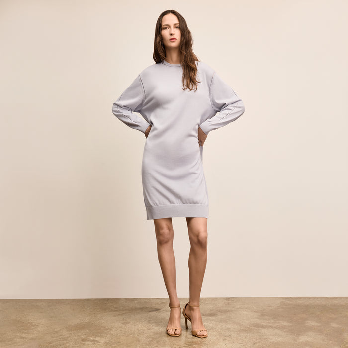 Woman wearing a light gray dress against a plain background