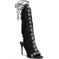 Black fringe knee high boots with cross straps and stiletto heels.