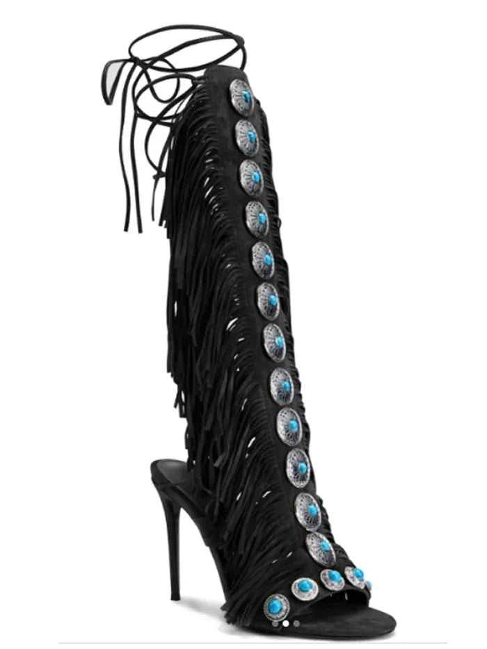 Black fringe knee high boots with cross straps and stiletto heels.