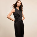 Woman wearing a black sleeveless dress against a beige background | Lead
