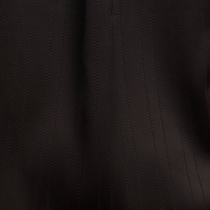 Person wearing a black satin shirt on a beige background