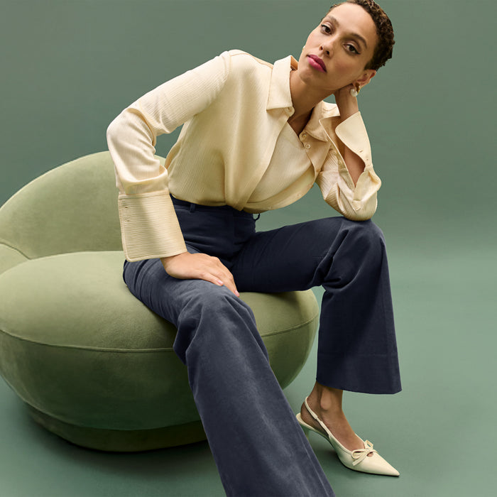 Woman sitting on a green chair against a green background