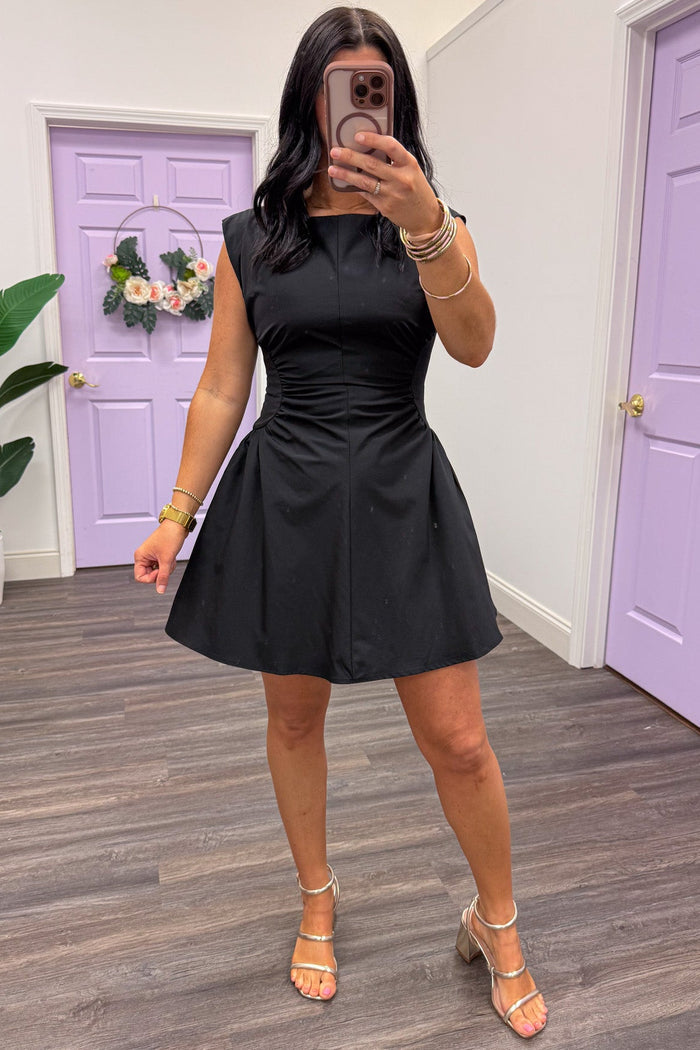 solid black sleeveless mini dress with cinched side panels at waist and flowy skirt