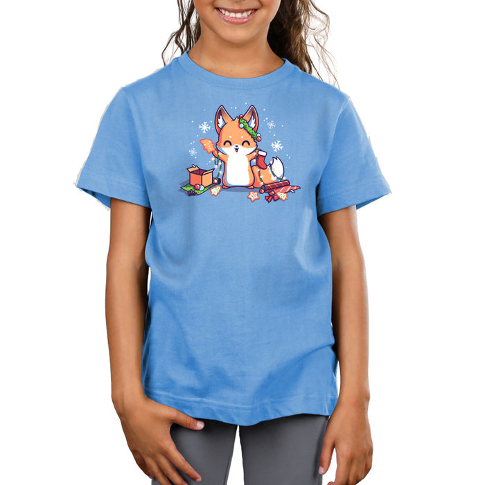 Premium Cotton T-shirt_TeeTurtle It's That Time of Year light blue t-shirt featuring a cheerful fox with green garland around its left ear surrounded by snowflakes and holding a red holiday stocking in one hand a Christmas cookie and a string of lights in the other. On the floor is red gift wrap, a red bow, Christmas cookies and a brown box on top of green gift wrap.