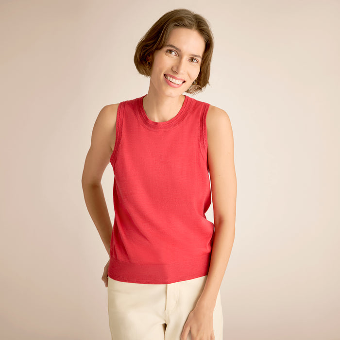 Woman wearing a red sleeveless top against a beige background | Lead